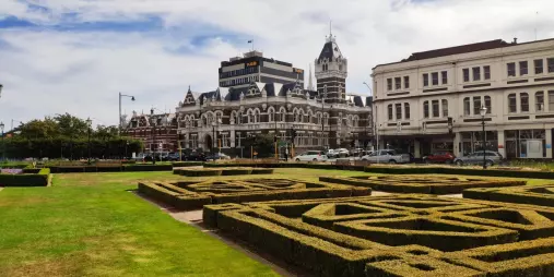 Historic Dunedin Railway Station behind the formal hedges of Anzac Square Gardens.