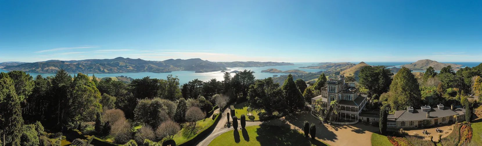Panoramic aerial view of Larnach Castle and Gardens on the Otago Peninsula with Otago Harbour in the background, Dunedin, New Zealand