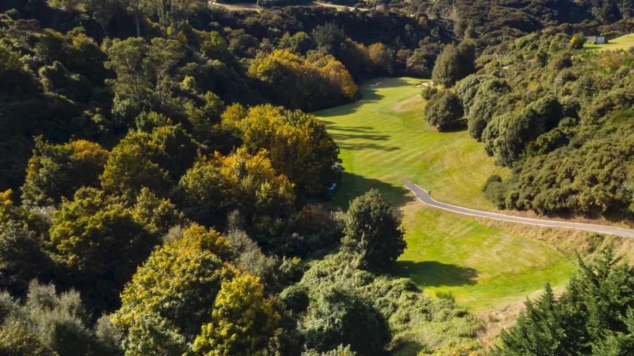 Aerial view of Otago Golf Course in Dunedin, New Zealand, surrounded by lush green fairways and dense forest.