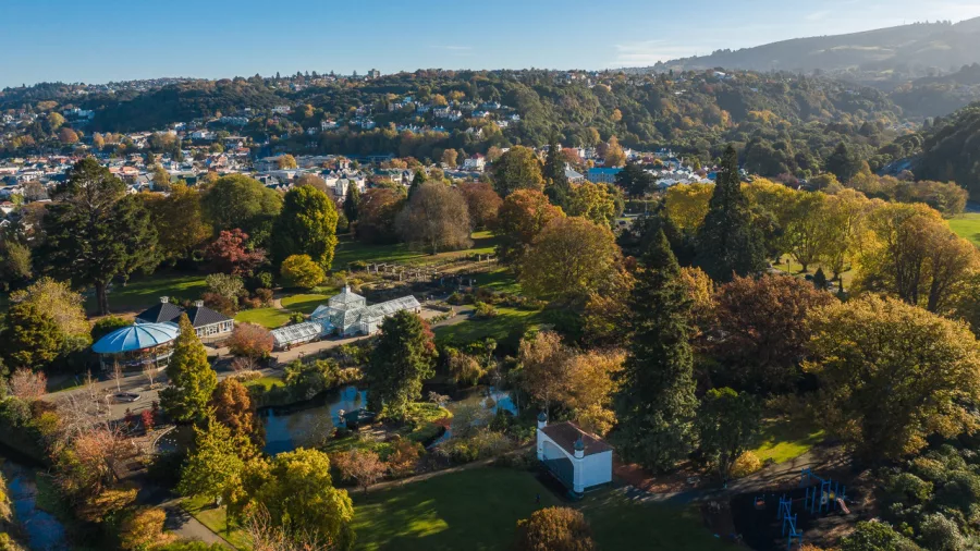 Aerial view of Dunedin Botanic Garden surrounded by trees and cityscape.