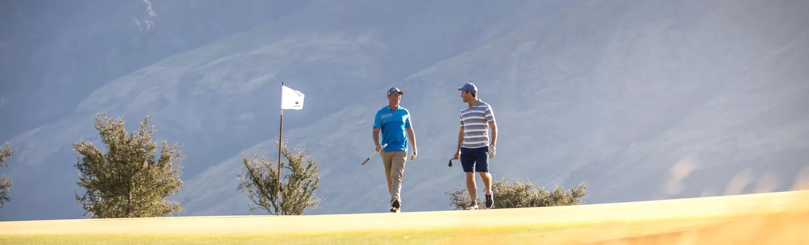 Two golfers walking on the fairway at Jack’s Point Golf Course in Queenstown with mountain backdrop