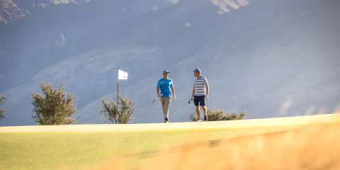 Two golfers walking on the fairway at Jack’s Point Golf Course in Queenstown with mountain backdrop