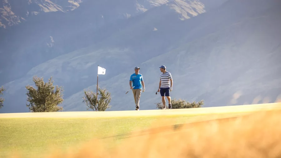 Two golfers walking on the fairway at Jack’s Point Golf Course in Queenstown with mountain backdrop