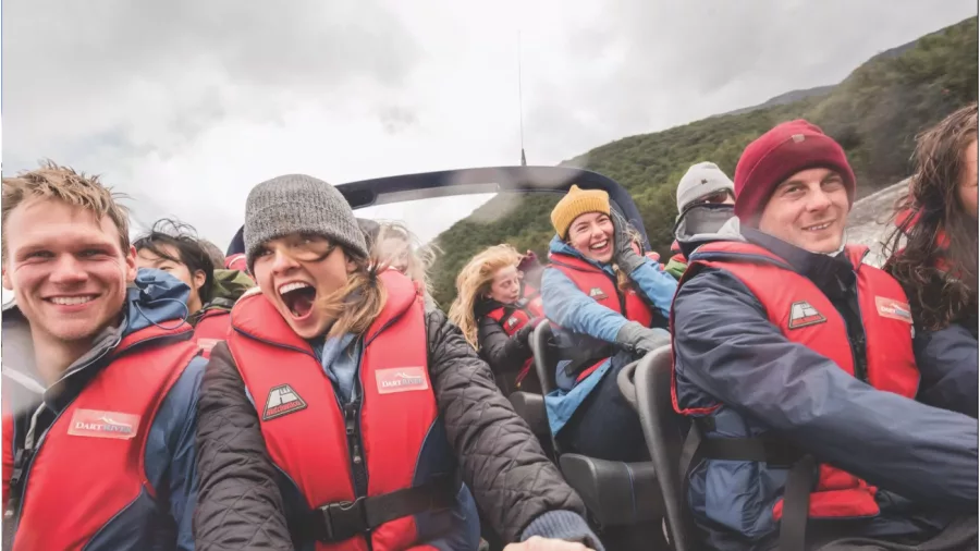 Excited passengers wearing life jackets during a thrilling Dart River jet boat ride near Glenorchy.