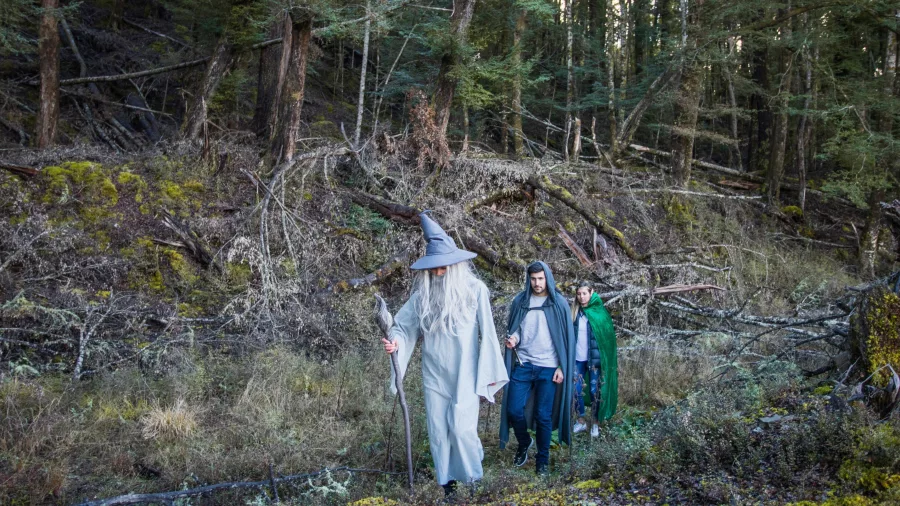 Tour guests dressed in Lord of the Rings costumes walking through forest near Glenorchy