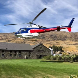 Helicopter landing outside Cardrona Distillery surrounded by rugged Otago hills.