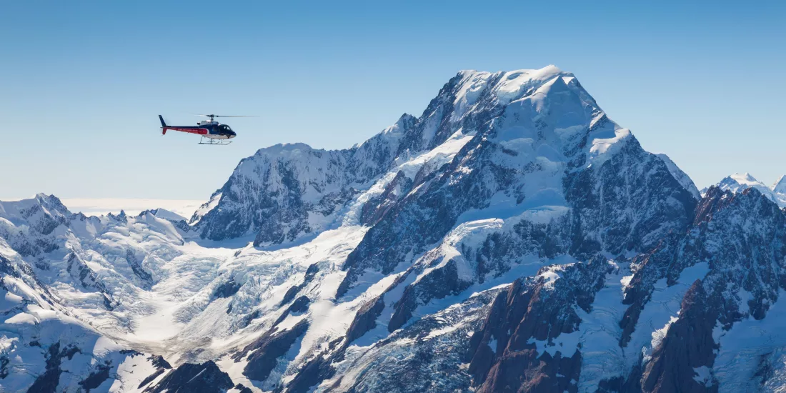 Helicopter flying near the summit of Aoraki/Mount Cook with clear blue skies