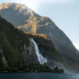 Bowen Falls plunging into the fjord with rugged cliffs and morning light in Milford Sound