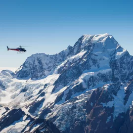 Helicopter flying near the summit of Aoraki/Mount Cook with clear blue skies