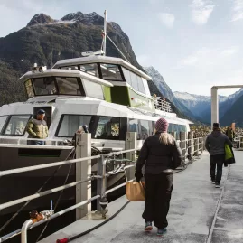 Tour guests walking towards a Milford Sound nature cruise boat at the marina