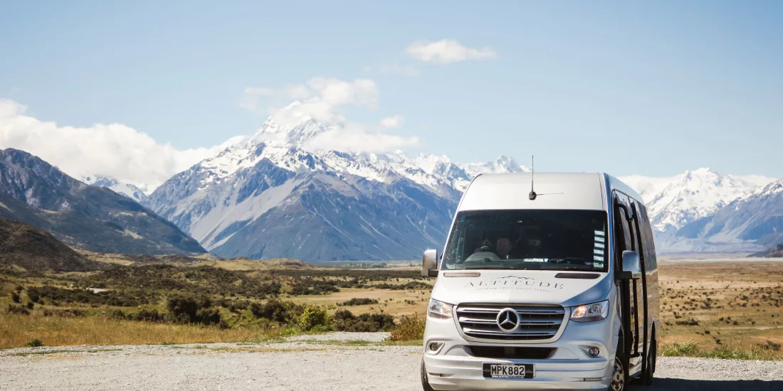 Premium small group tour van parked with Mount Cook and Southern Alps in the distance.
