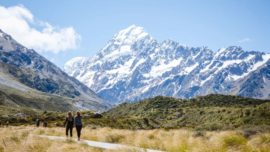 Couple walking the Hooker Valley Track with Mount Cook in the distance.