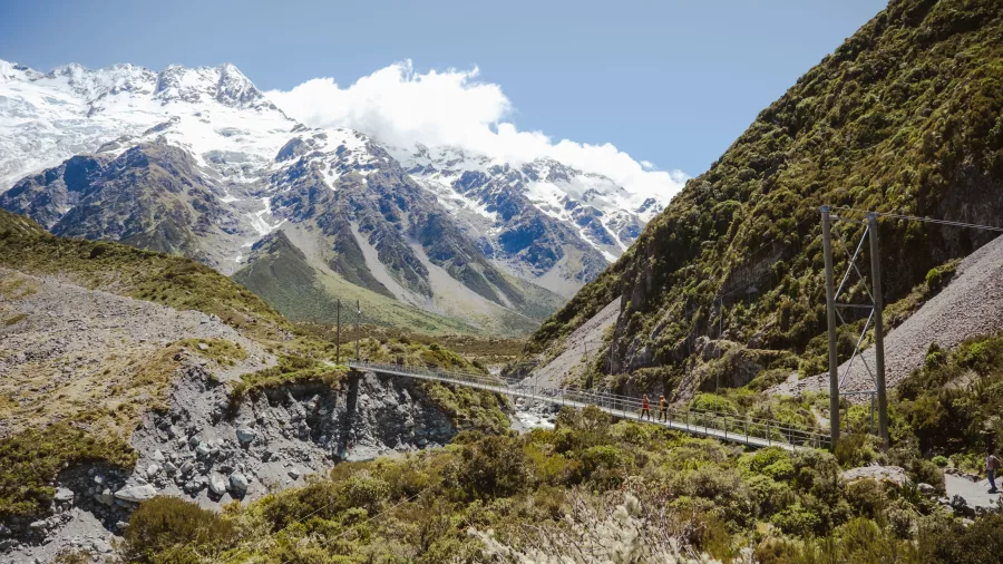 Hooker Valley swing bridge with snowy alpine peaks in the background.
