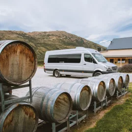 Twilight wine tour van parked beside wine barrels outside Kinross Winery in Gibbston Valley