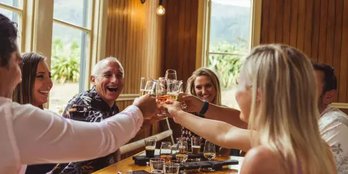 Group toasting glasses during a guided beer tasting at a Gibbston Valley stop on the twilight tour