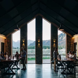 Guests enjoying wine tastings inside Kinross’s modern tasting room with tall windows framing vineyard views