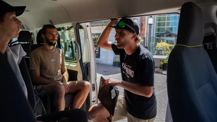 Canyoning guide giving safety briefing to guests in transport van