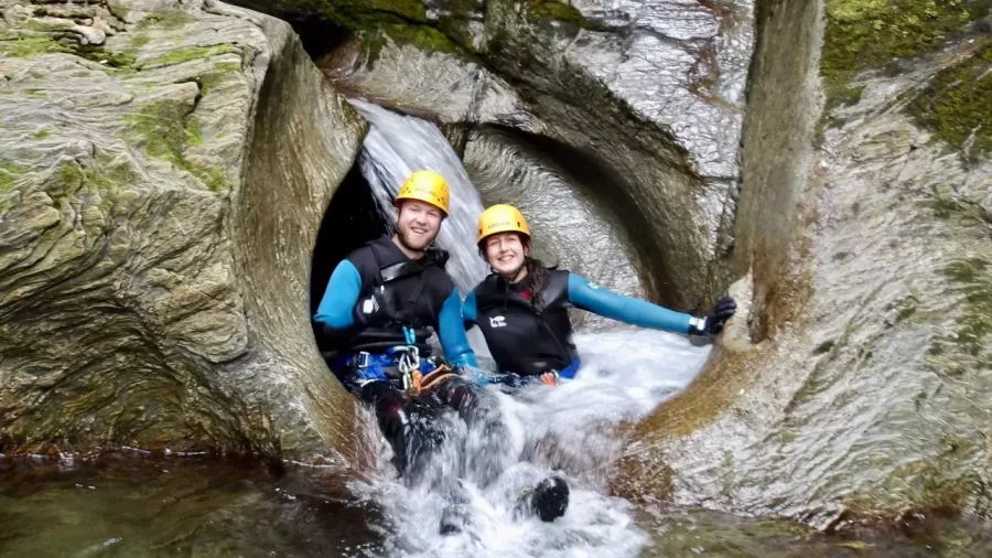 Two canyoners smiling at base of natural water tunnel