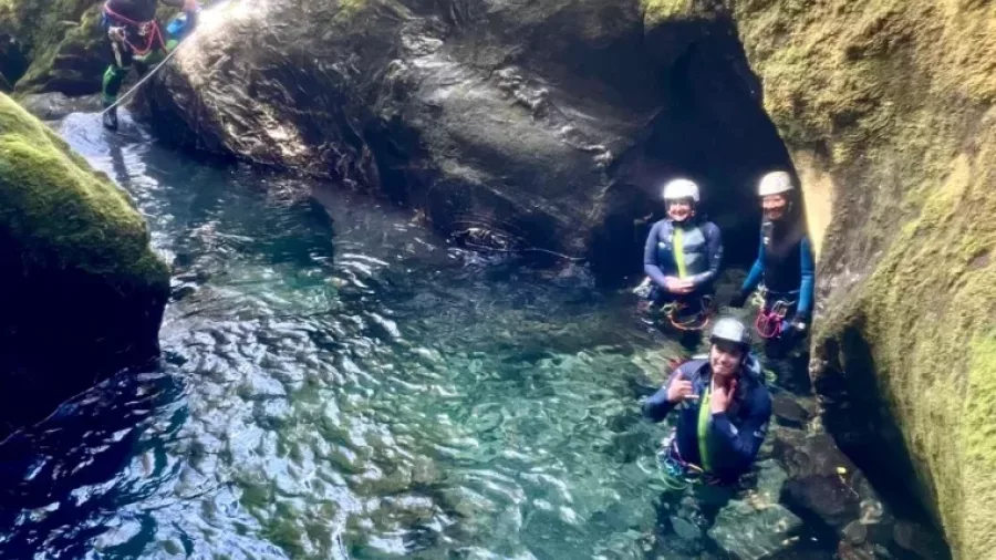 Canyoners standing in crystal-clear alpine canyon stream