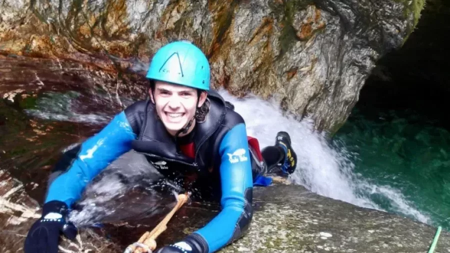 Smiling canyoner gripping rope on sloped canyon rock