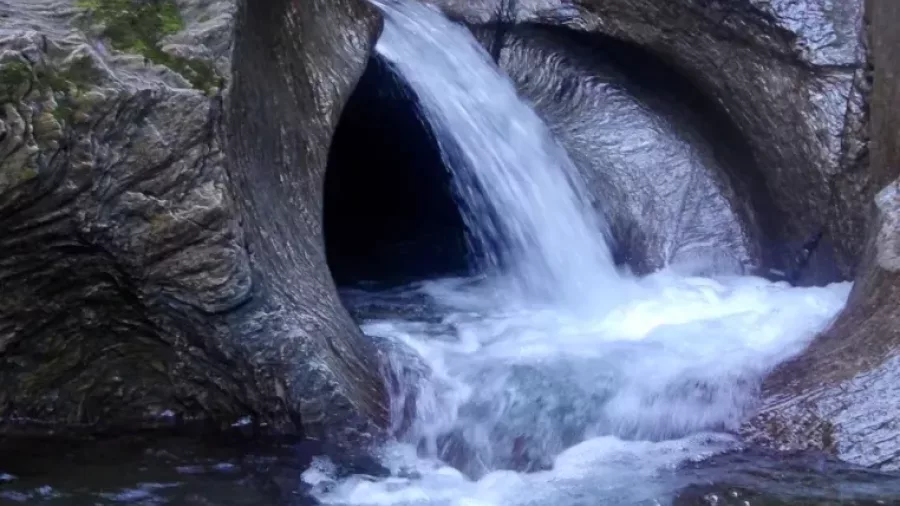 Canyon waterfall rushing from natural rock tunnel