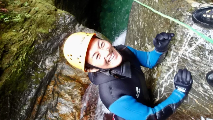 Female canyoner smiling mid-canyon climb