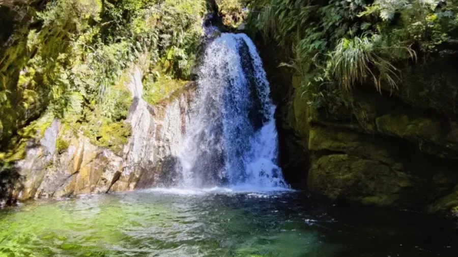 Sunlight hitting waterfall above green canyon pool