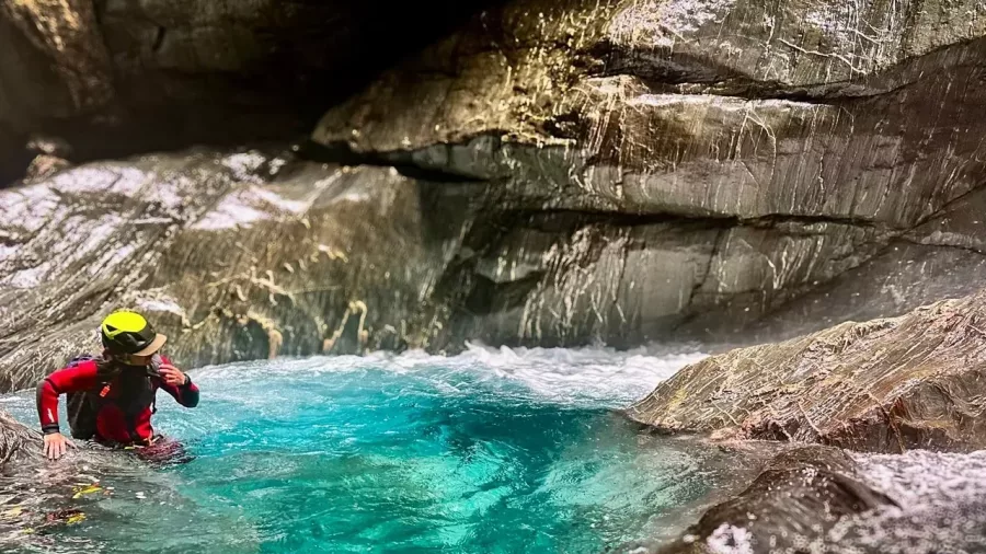 Canyoner pausing in vibrant blue canyon pool