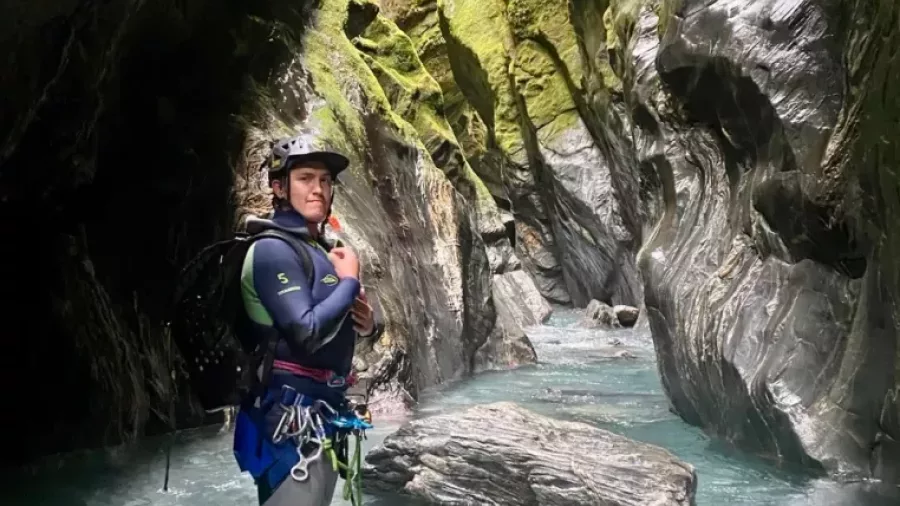 Canyoner standing in stream surrounded by mossy canyon walls