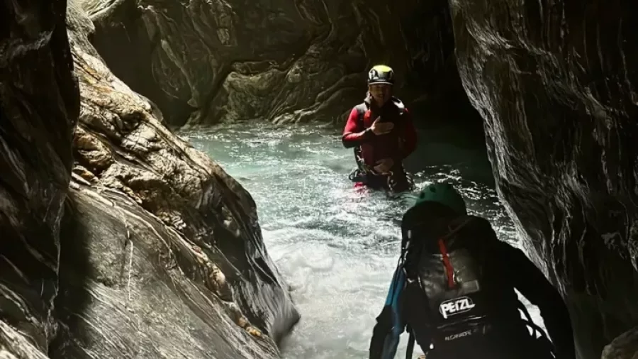 Two canyoners walking through tight rocky water channel