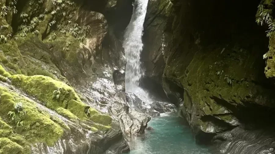 Hidden waterfall framed by towering mossy cliffs