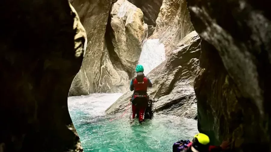 Canyoners swimming through emerald canyon pool