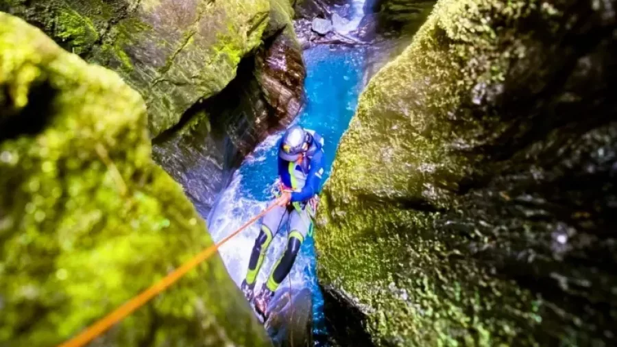 Canyoner descending narrow canyon with safety rope
