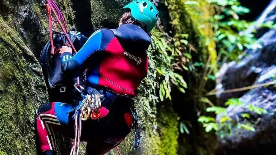 Canyoner abseiling a mossy canyon wall