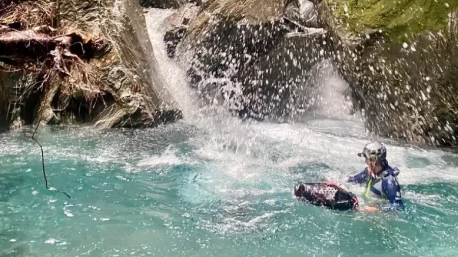 Canyoner swimming in splash zone under waterfall