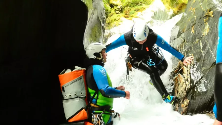 Canyoning guide helping participant into narrow water channel