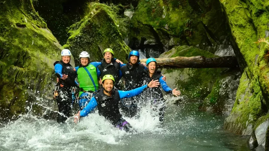 Group of canyoners splashing in mossy canyon pool