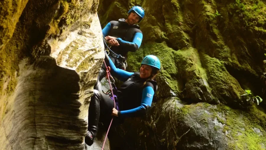 Two smiling canyoners on vertical rock wall