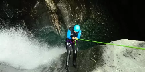 Canyoner abseiling towards canyon waterfall pool