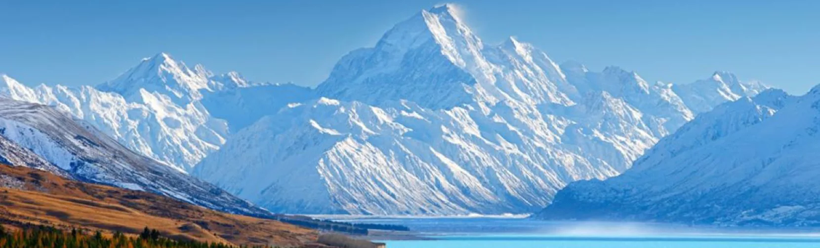 Snow-covered Mount Cook rising behind Lake Pukaki with autumn colours in the foreground