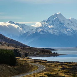Scenic road leading away from Mount Cook alongside the blue waters of Lake Pukaki