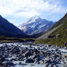 Hooker River flowing over boulders with Mount Cook in the background on a summer day