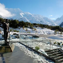 Statue of Sir Edmund Hillary in Mount Cook Village with snow-covered mountains behind