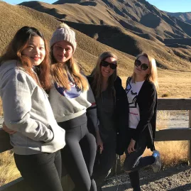 Group of friends at a lookout point in Lindis Pass with golden hills in the background