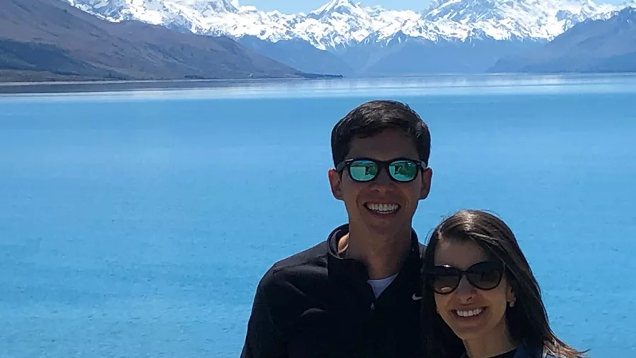 Couple posing in front of the vibrant blue waters of Lake Pukaki with Mount Cook and the Southern Alps in the background