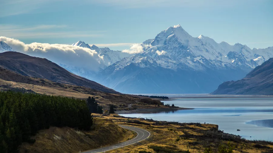 Scenic road winding along Lake Pukaki with Mount Cook and the Southern Alps in the background