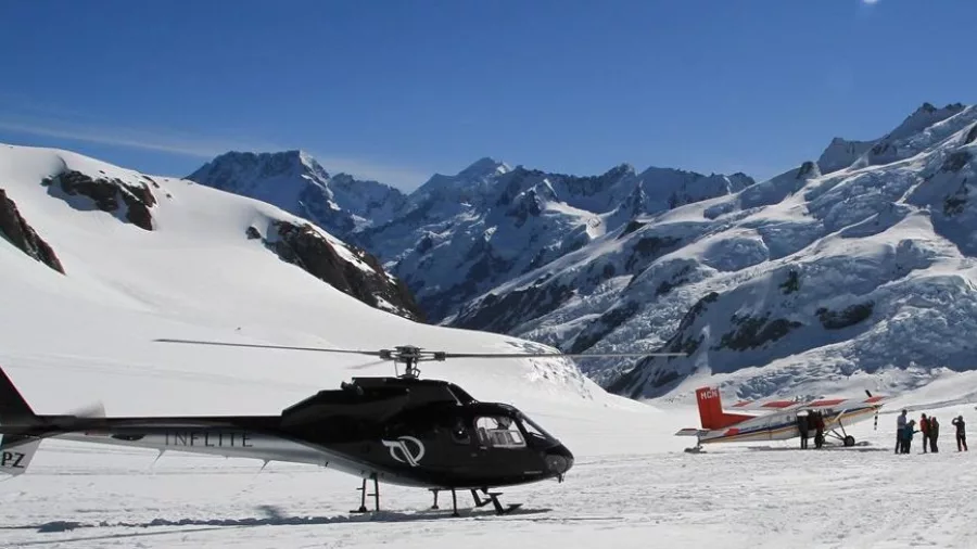 Helicopter and light aircraft on a snow-covered landing site near Mount Cook in the Southern Alps