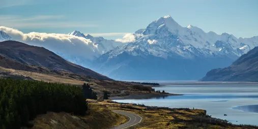 Scenic road leading away from Mount Cook alongside the blue waters of Lake Pukaki