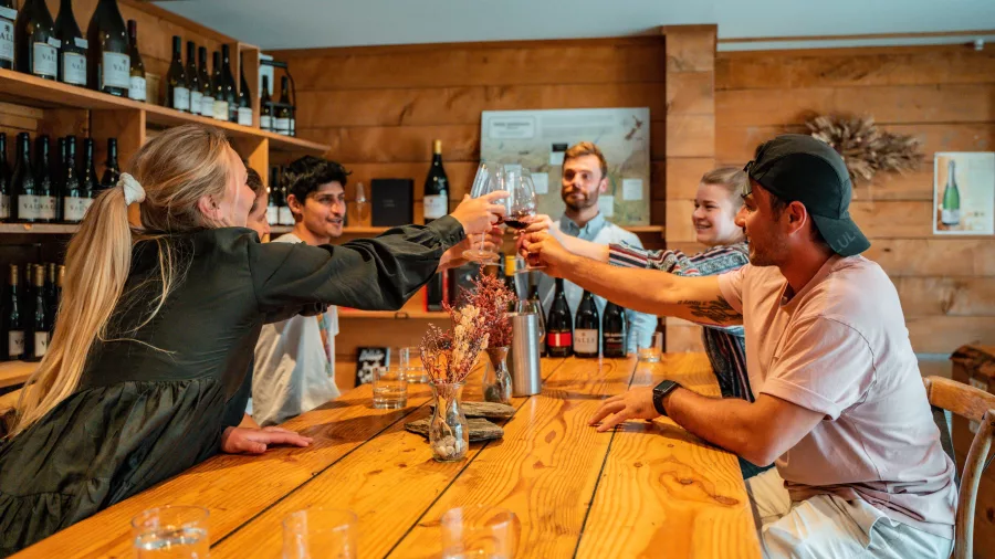 Group of friends clinking glasses inside the Kinross cellar door in Central Otago.