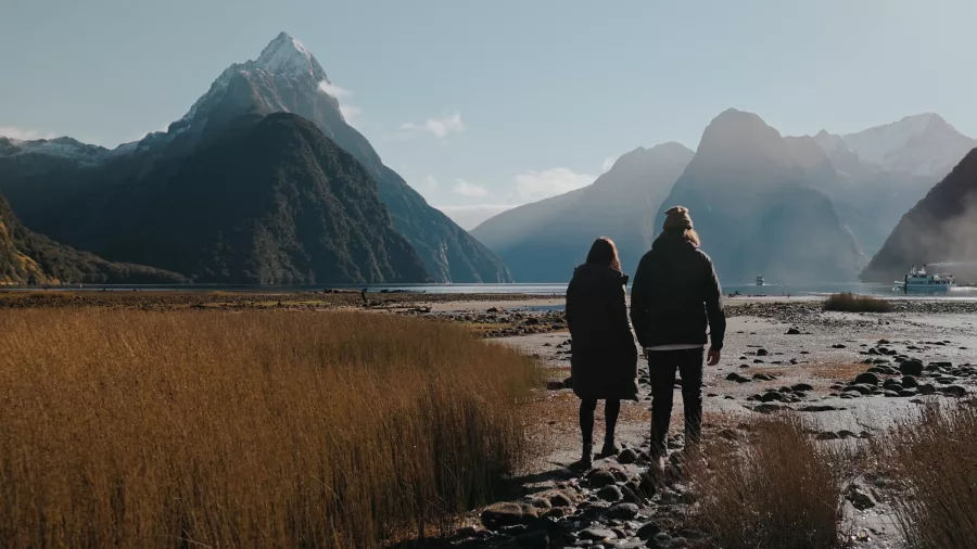 Couple walking along the Milford Sound foreshore after scenic flight